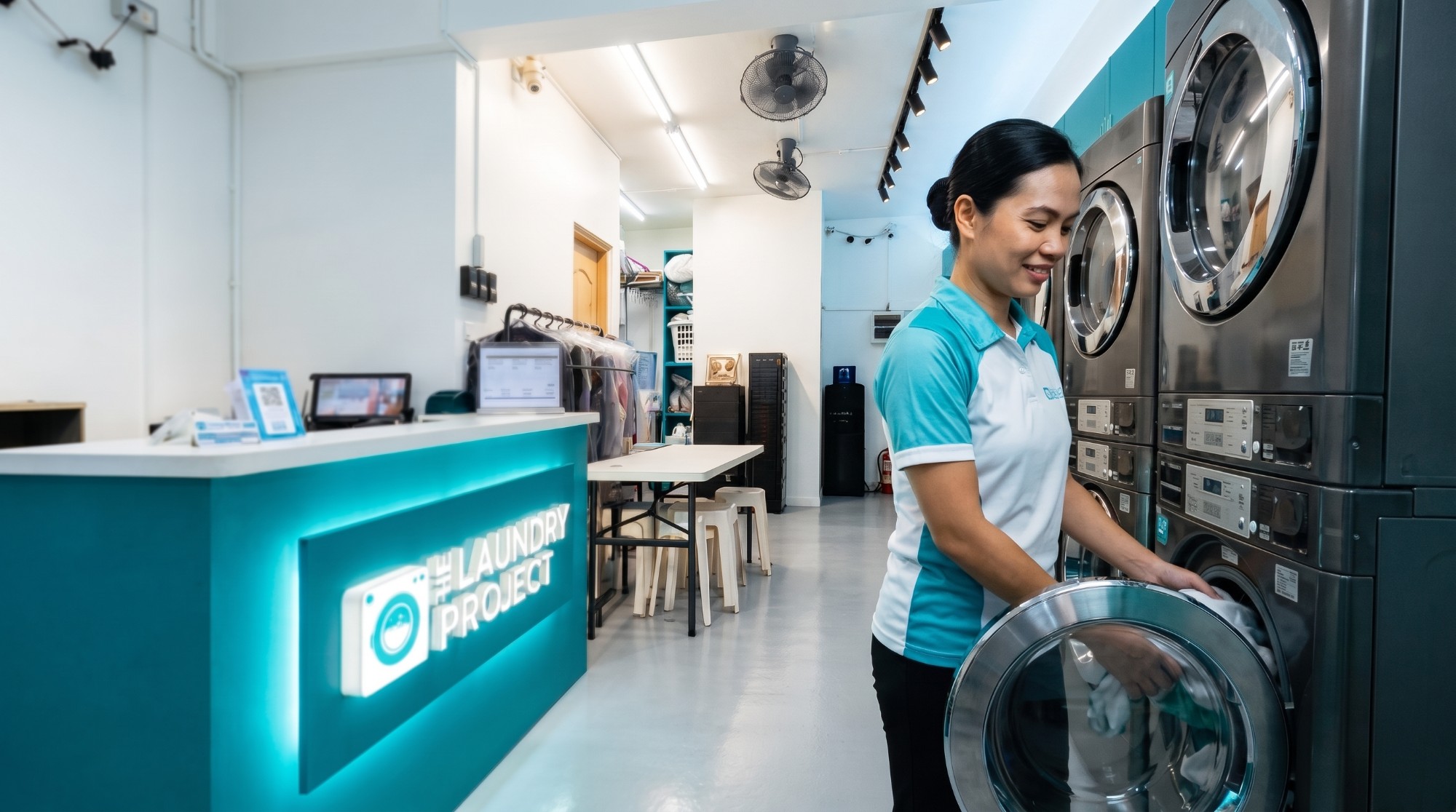 The Laundry Project staff member loading a washing machine in the Makati shop